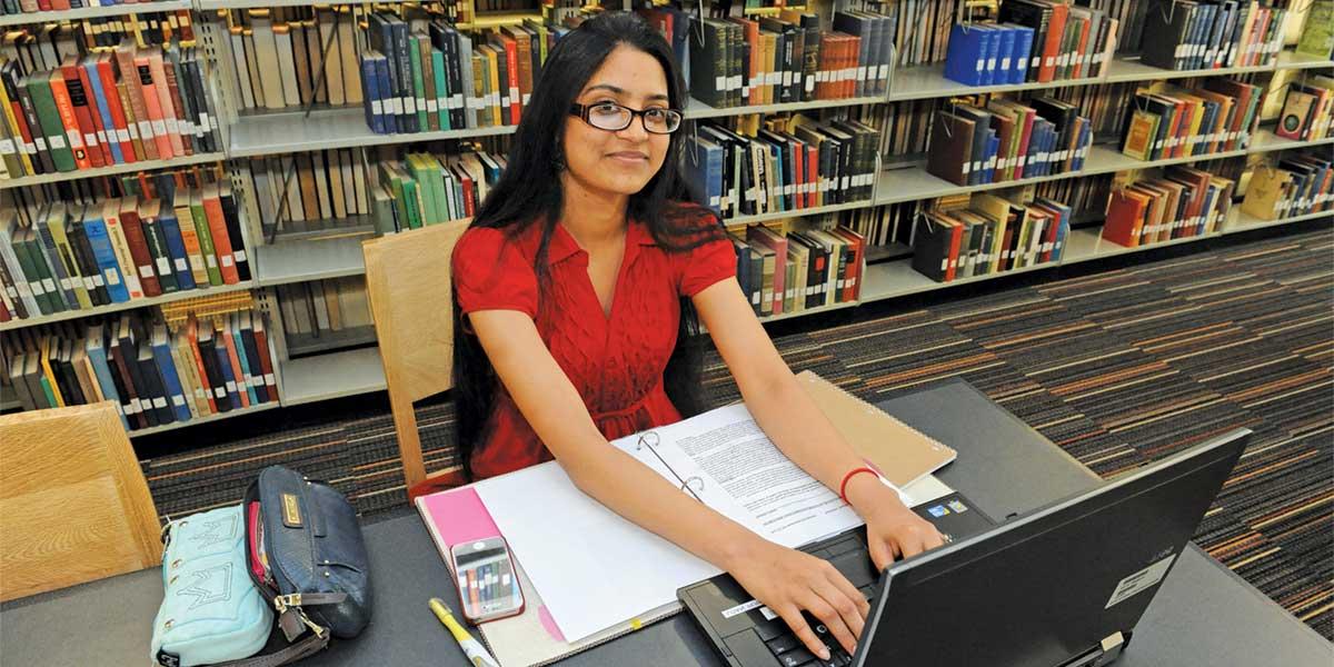 female student in library with laptop computer